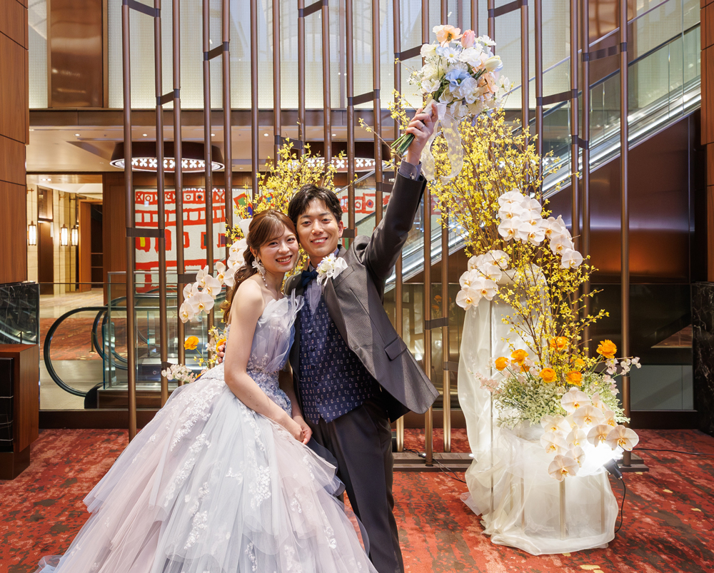 花束を掲げた新郎様と笑顔の新婦様