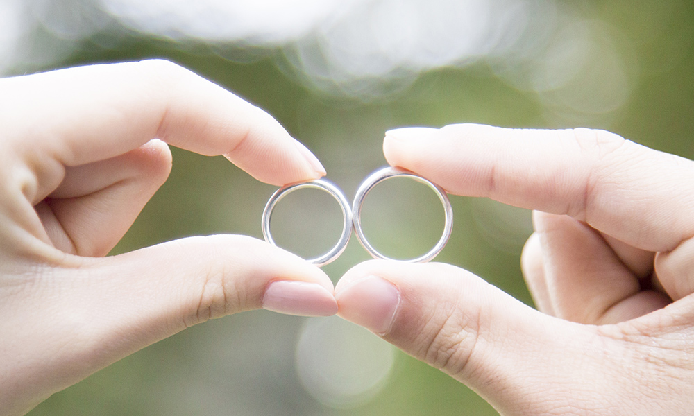 結婚指輪を持っているカップルの手