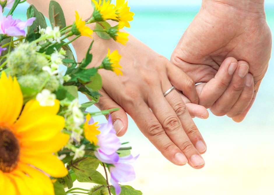 黄色や白の花とゆびきりをする夫婦