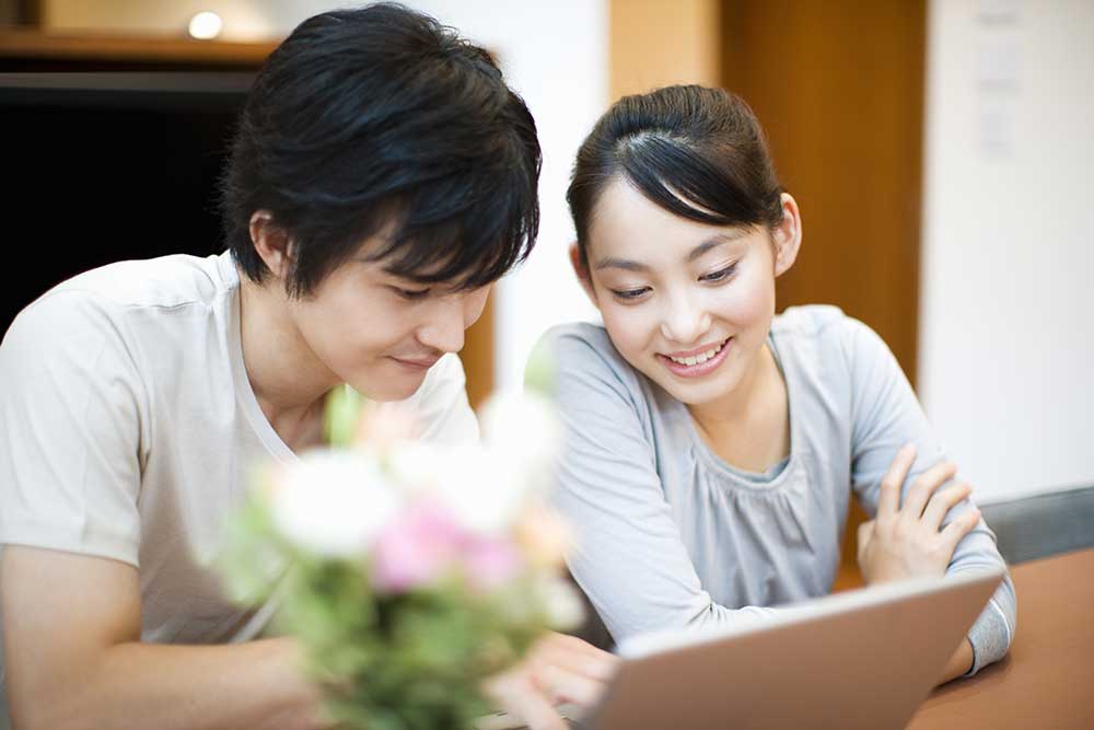 パソコンをのぞき込む笑顔の男女