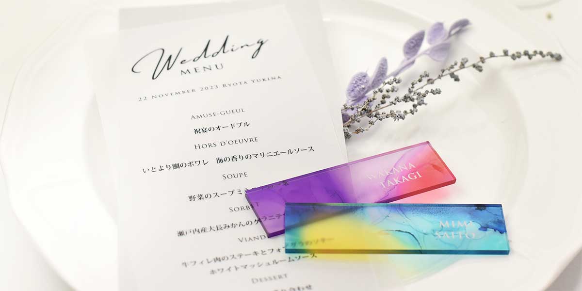 お皿の上にのっている結婚式のメニュー表とマーブル模様がおしゃれなアクリル席札