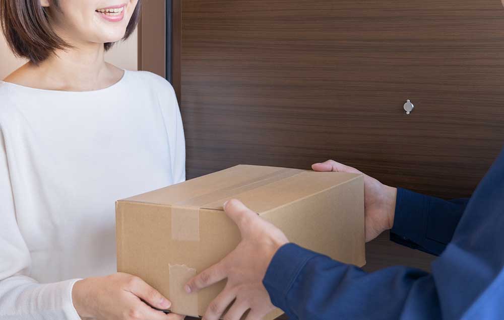 宅配便を配達業者から受け取る女性