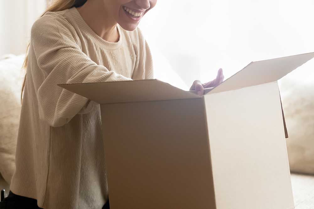 笑顔で段ボール箱の中身を確認している女性