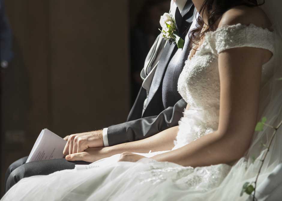 結婚式で挨拶スピーチをの原稿を持つ新郎と手を握る新婦