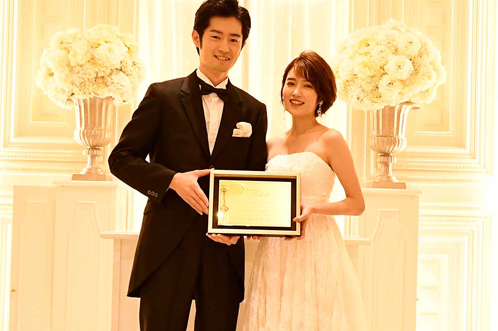 アクリルゴールドの結婚証明書を手に持ち微笑む新郎新婦