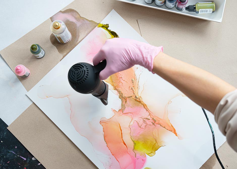 ドライヤーを使ってアルコールインクアートの模様を広げている