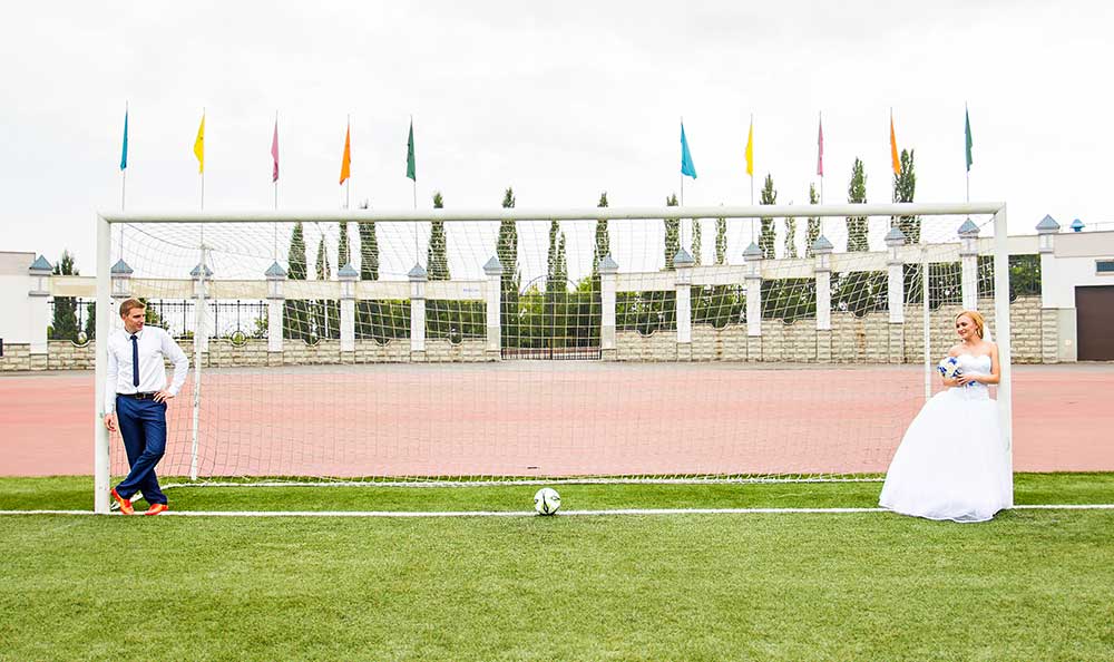 サッカーゴールの前で写真を撮る新郎新婦