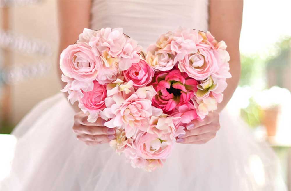 ピンクのフラワーアレンジが付いたお手紙ボードを両手で持つ花嫁