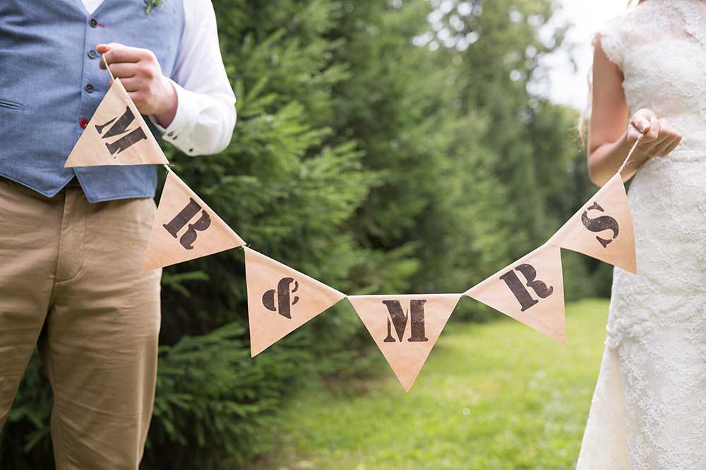 ガーランドで作った新郎新婦のサインを手に持つ新郎新婦