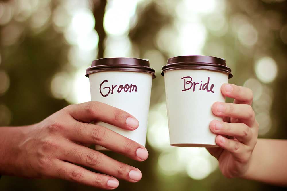 GroomBrideの文字入りのコーヒーカップを手に持つ新郎新婦