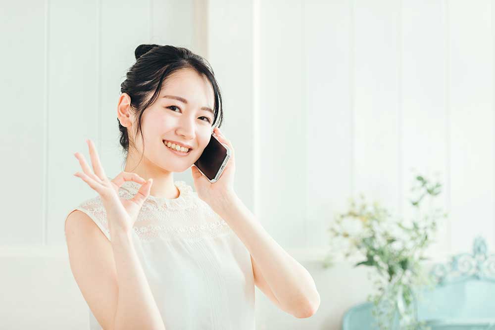 電話をかけながらOKサインをしている女性