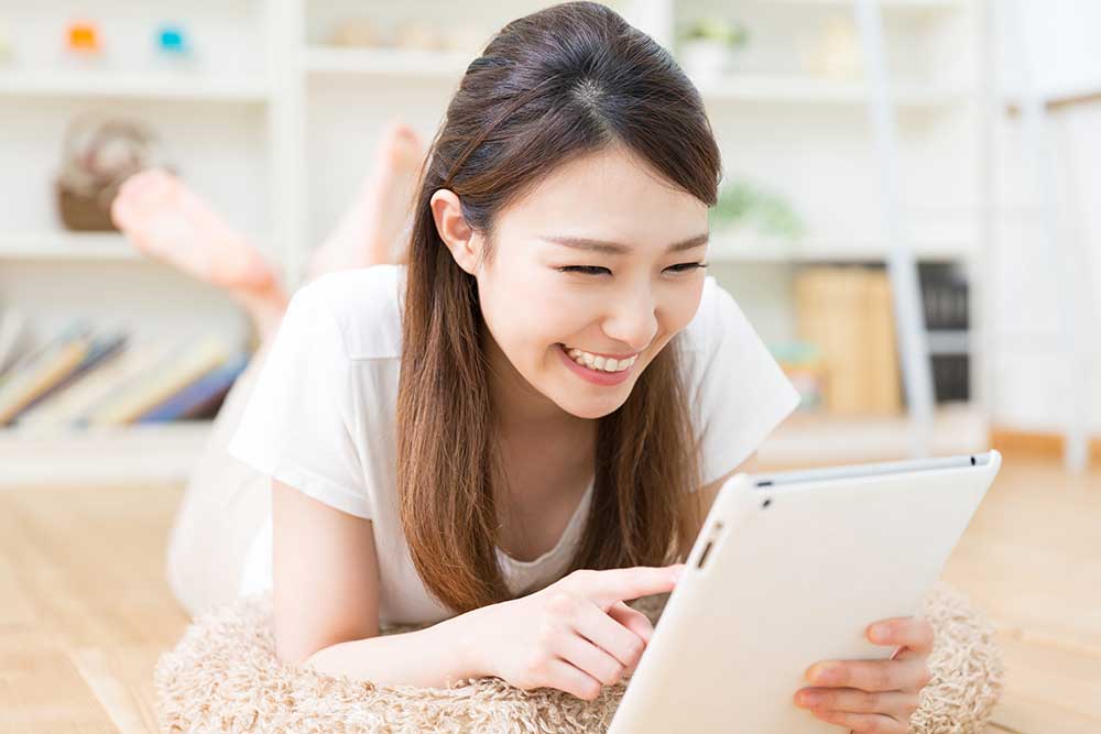 タブレットを笑顔で見る女性