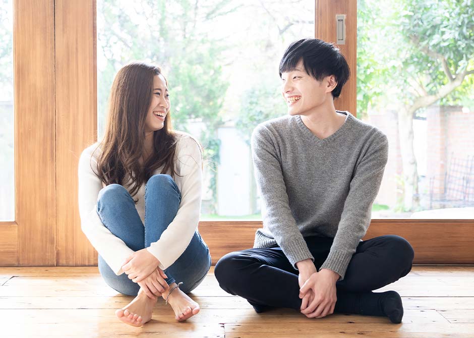 リビングに座って笑顔で見つめあうカップル