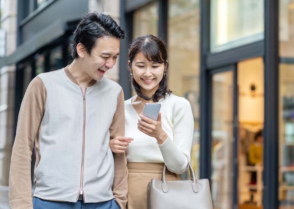 デートしながら一緒にスマホを見ている笑顔のカップル