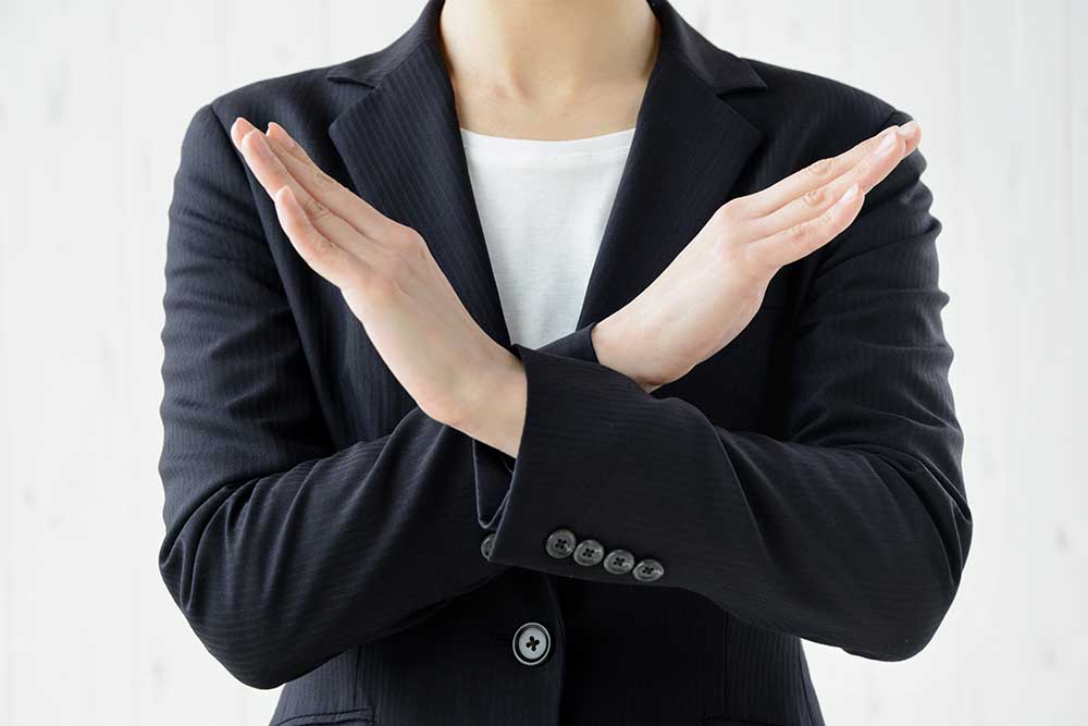 手の前でバツ印を作るスーツの女性