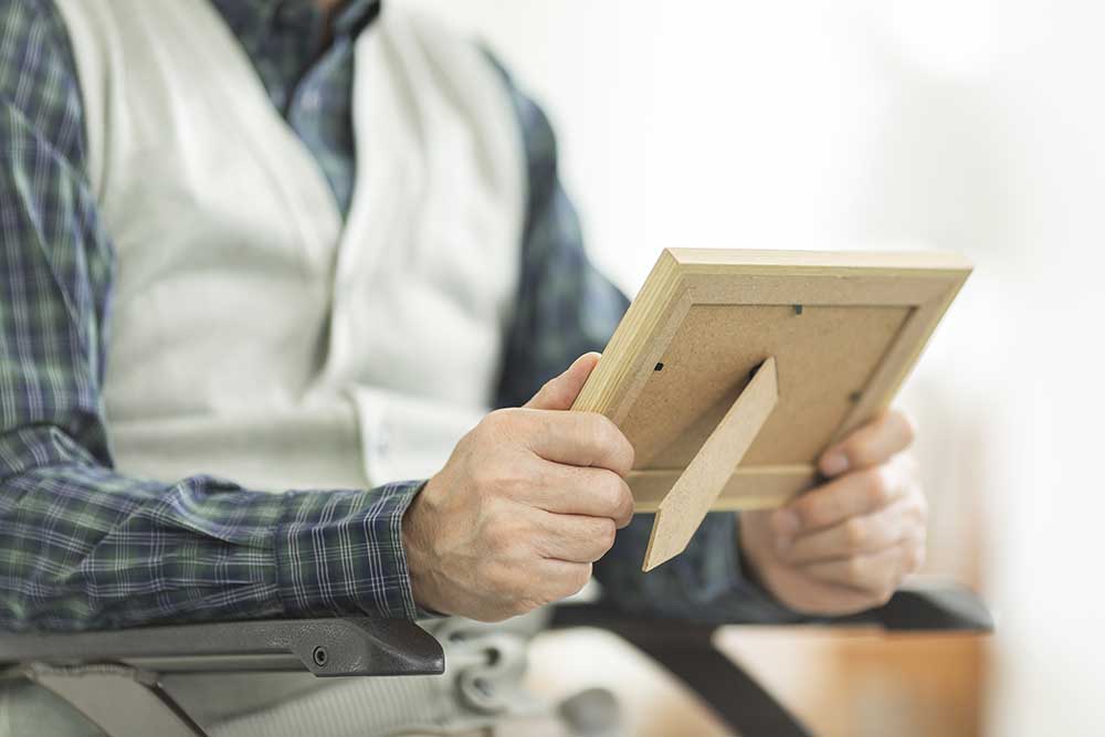 フォトフレームを手に持ち眺めるシニア男性