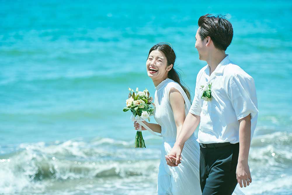 海辺をふたりで歩く幸せそうな新郎新婦