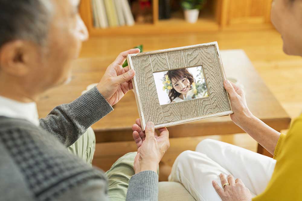 孫の花嫁姿の写真を見ている祖父母