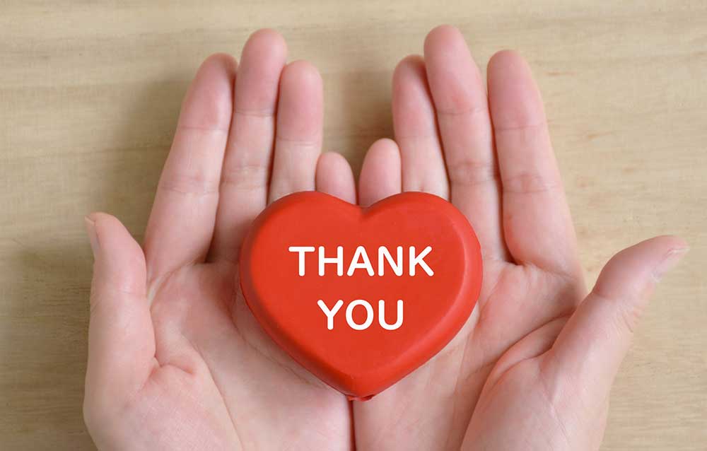 手のひらの上にThankyouと書かれた赤いハートを載せている
