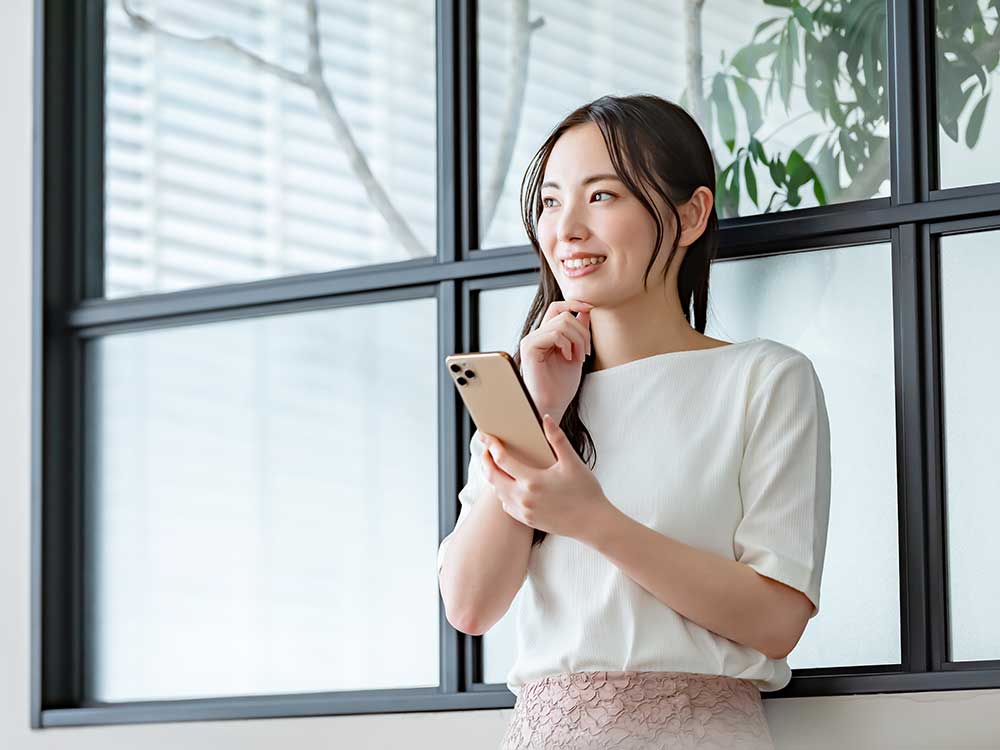 スマホを片手に考え事をしている女性