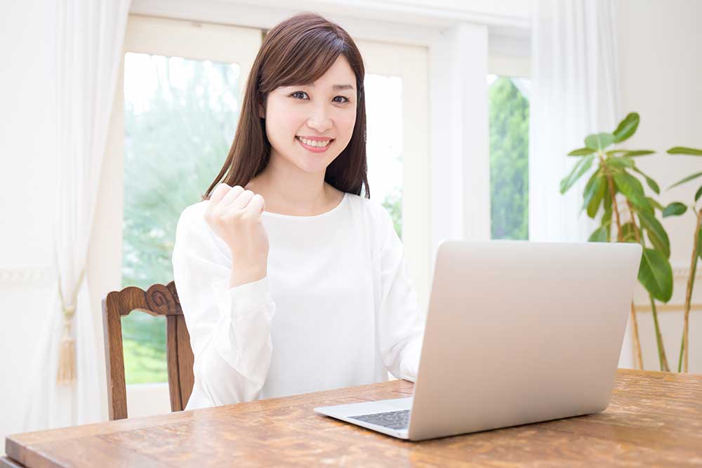 パソコンの前でガッツボーズをする椅子に座っている女性