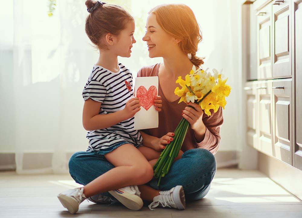 幼い娘からカードと黄色のお花をもらって嬉しそうにしている母親