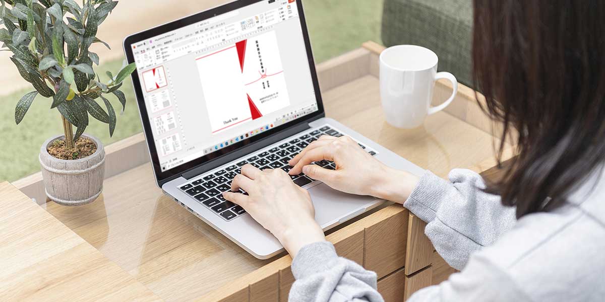 ノートパソコンで顔合わせ会しおりのデータを作成している女性