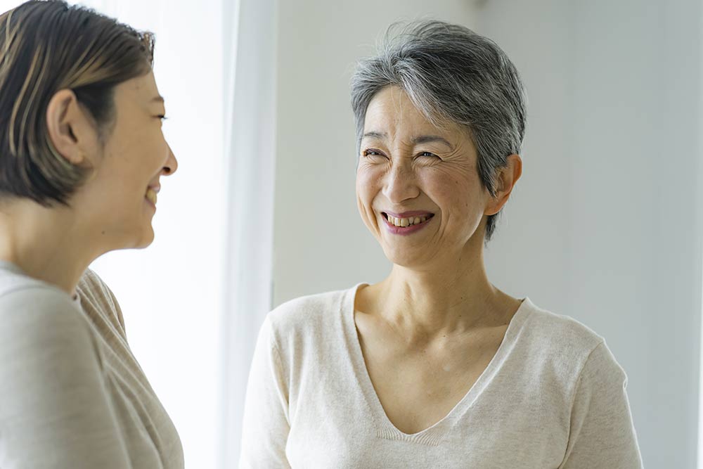 笑顔で会話する30代日本人女性とシニア女性