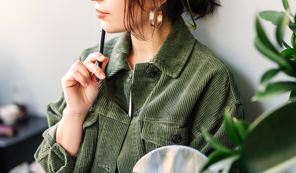 ペンを顎につけて考えている女性