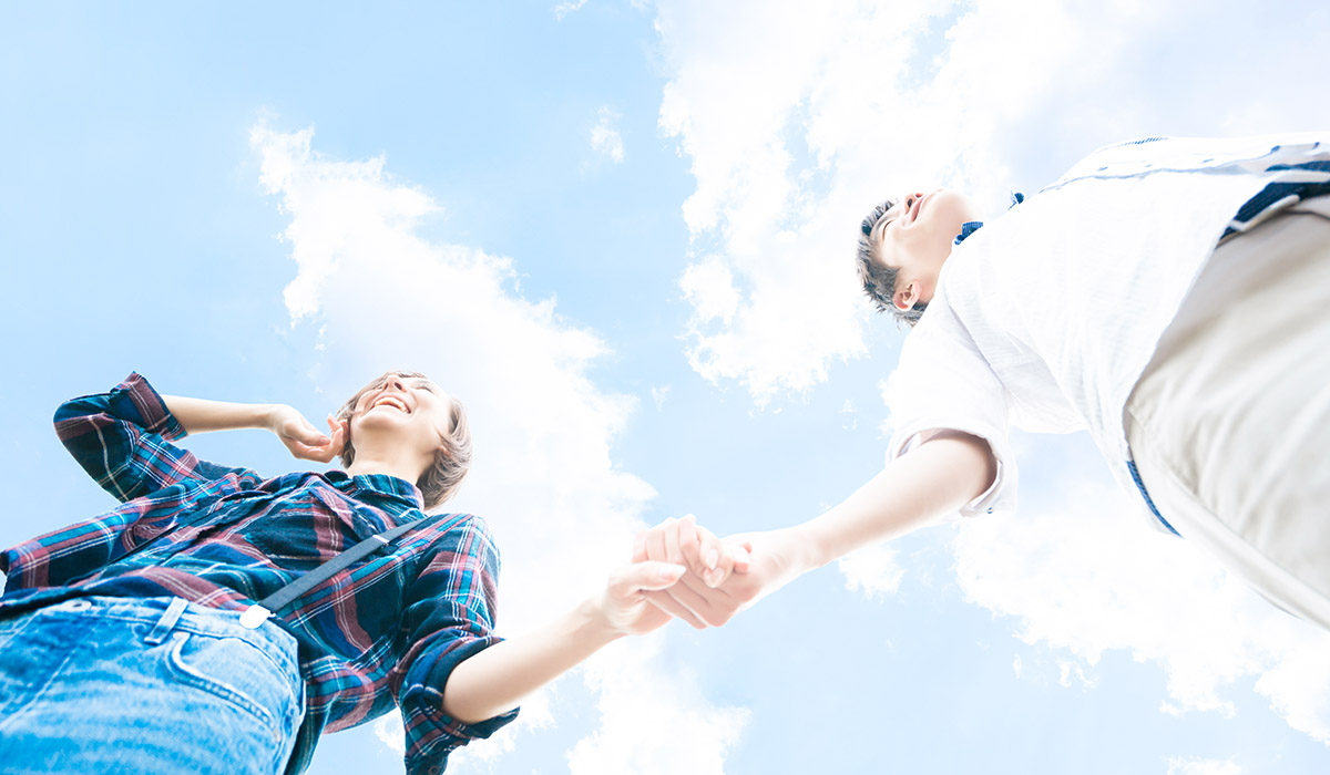 手をつないでいる青空の下のカップル