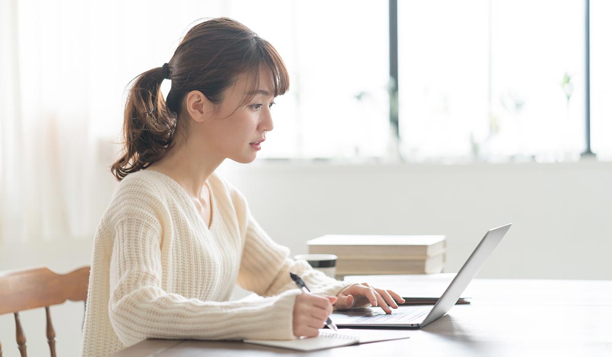 パソコンを見ながらメモを取る女性