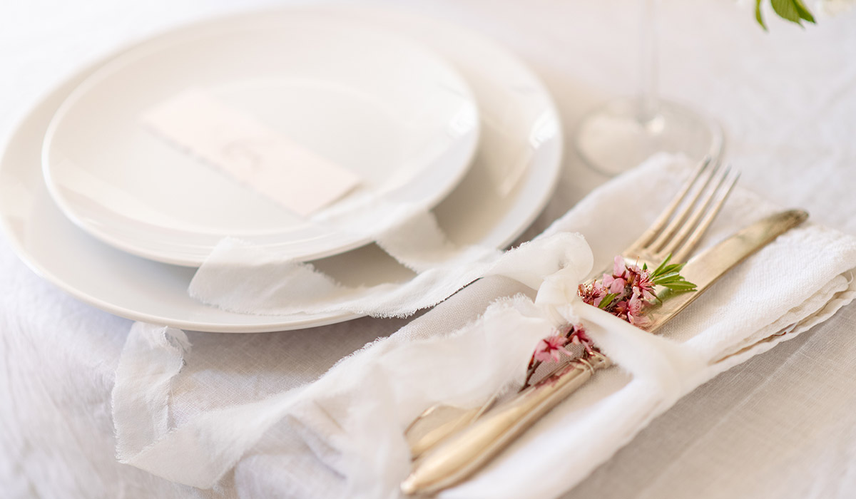 結婚式の披露宴会場のテーブル白くて丸いお皿に席札が乗っている