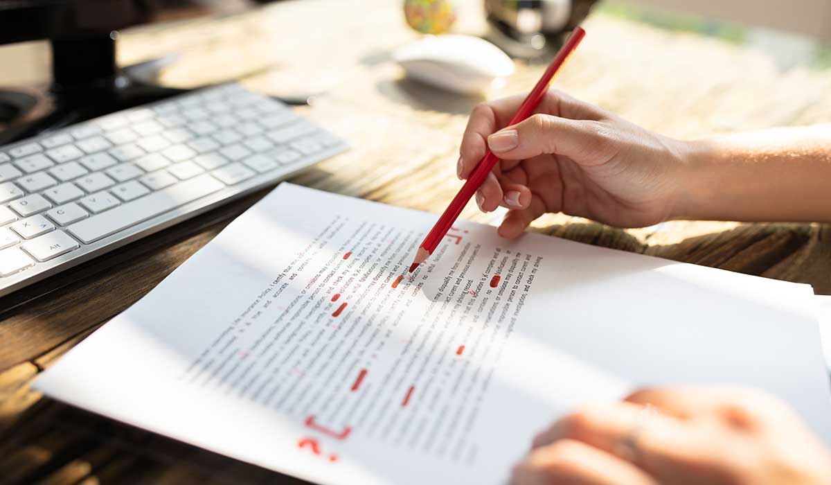 赤ペンを持って原稿を校正している