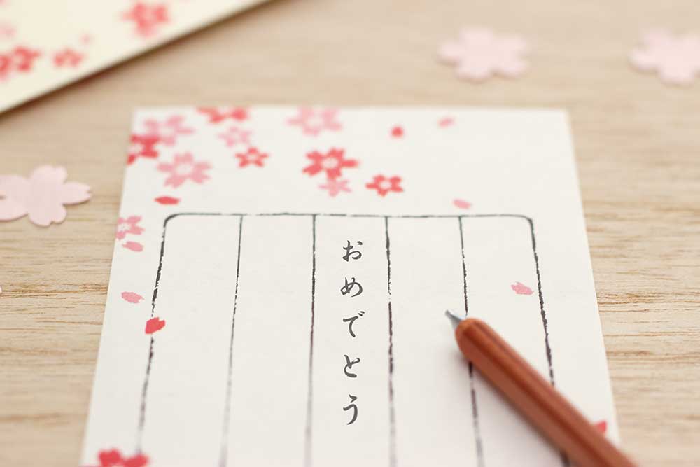桜柄の縦書き一筆箋におめでとうと書いている
