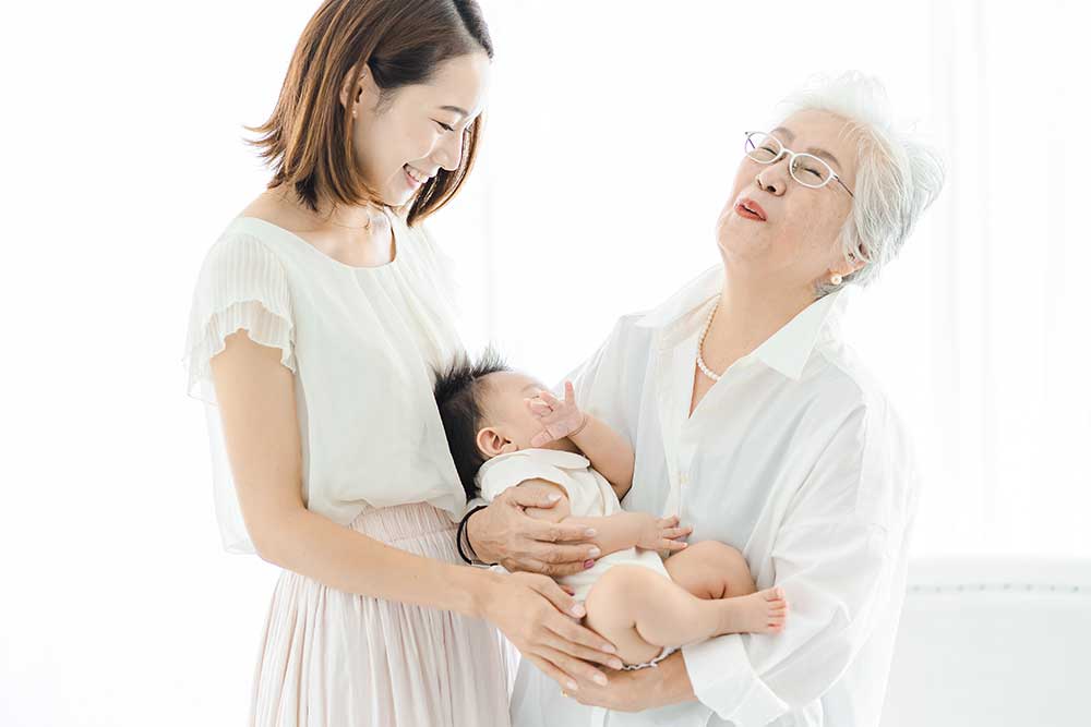 孫を抱き笑顔の三世代家族（母娘赤ちゃん）