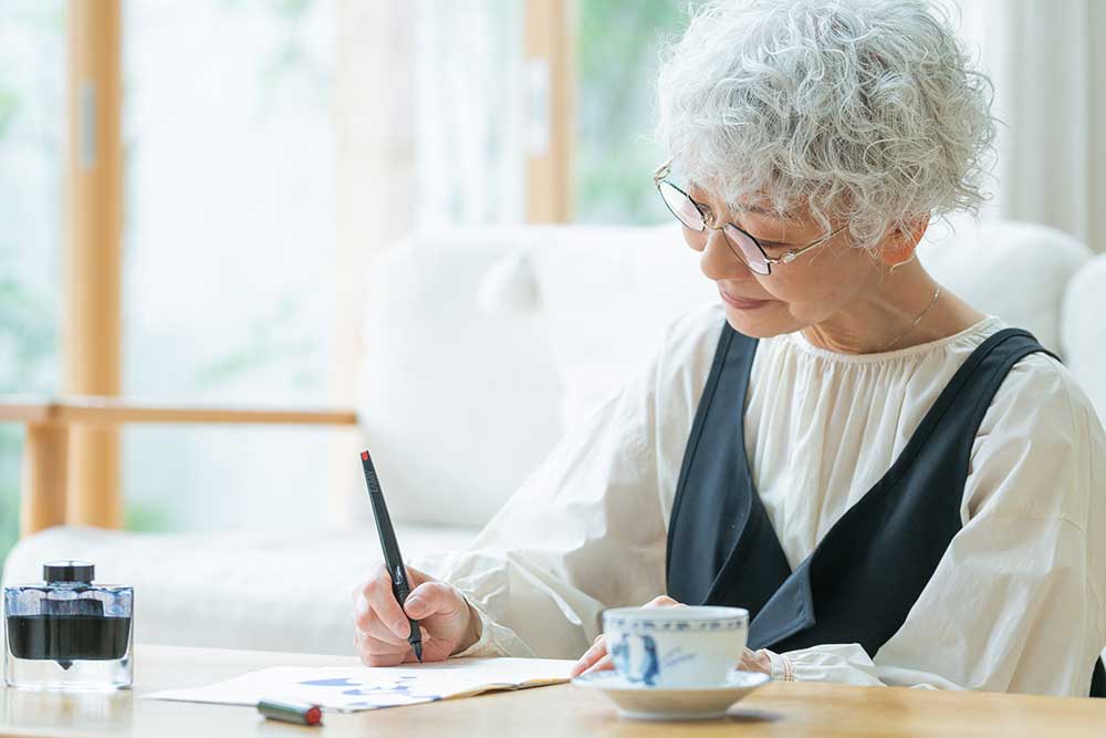 手書きを書いているシニア女性
