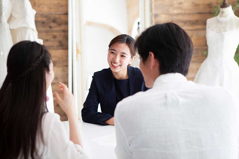 ウェディングプランナーと笑顔で話をしているカップル