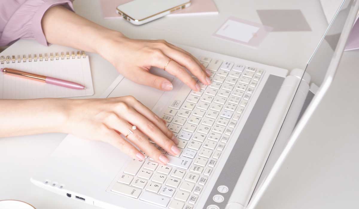 ノートパソコンのキーボードをたたいている女性の手元