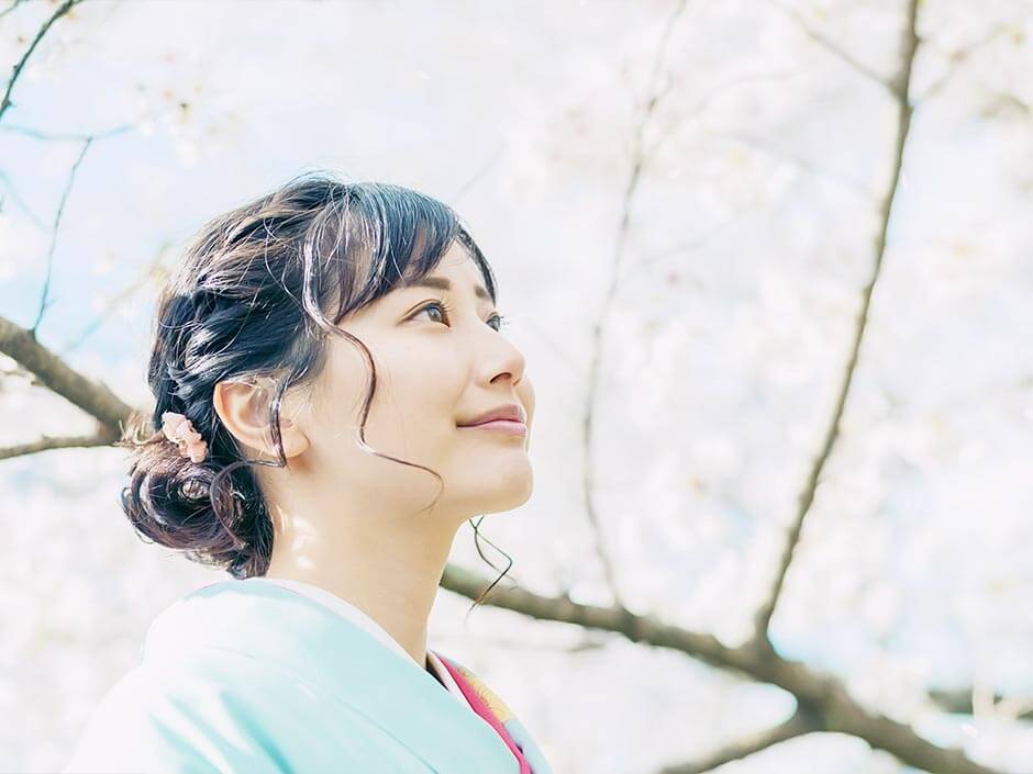 卒業式の日に桜の木の前にいる和装の女性