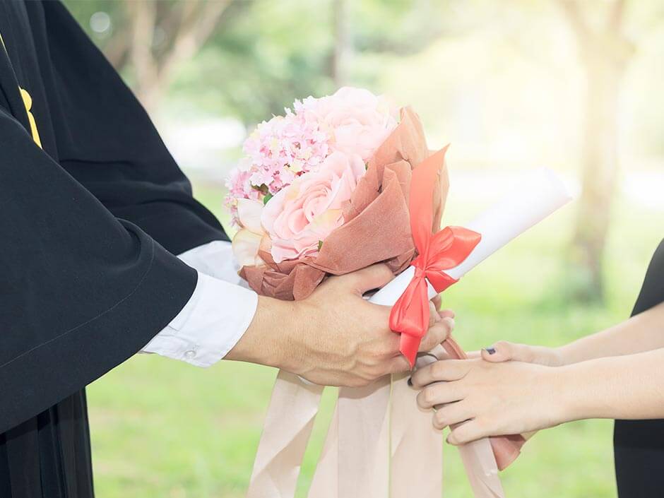 卒業式で親に花束を渡している
