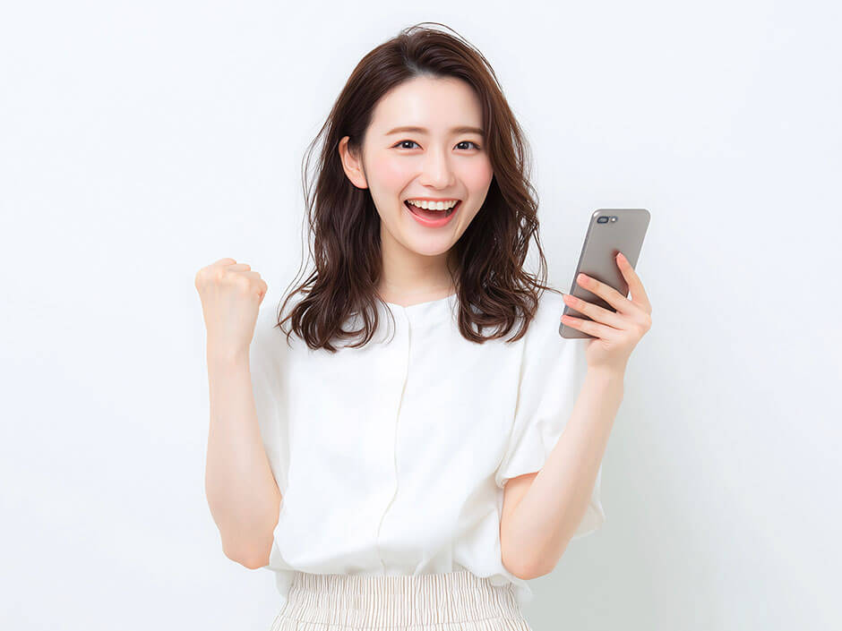 スマートフォンを持つガッツポーズをした笑顔の女性
