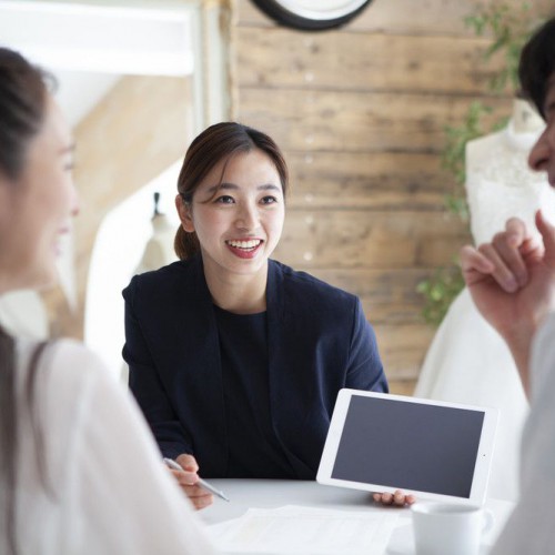 タブレットを片手に結婚式のプランを紹介するプランナー