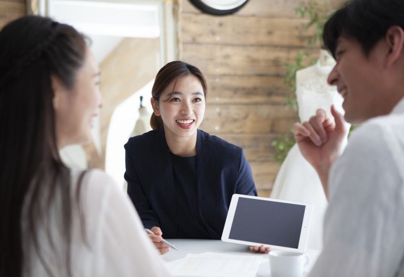 タブレットを片手に結婚式のプランを紹介するプランナー