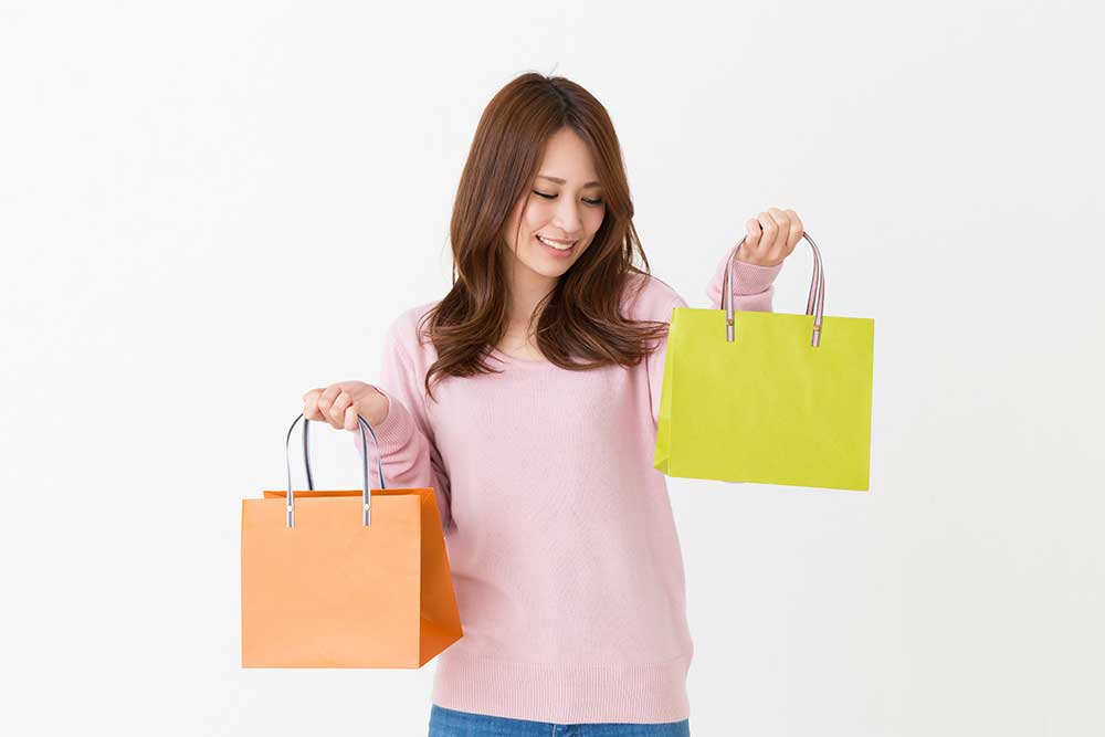 どちらの紙袋にするか迷う女性